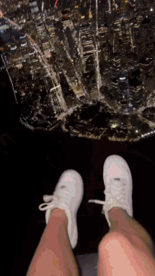 a person 's feet are shown in front of a city skyline at night