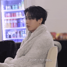 a young man wrapped in a white blanket is sitting in a chair