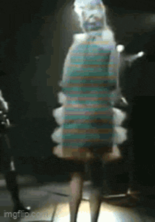 a woman in a blue dress is standing in a dark room