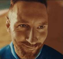 a man with a beard and a blue shirt is smiling