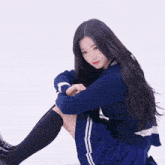 a girl with long black hair wearing a blue sweater and black knee high socks