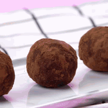 three chocolate truffles are on a white plate