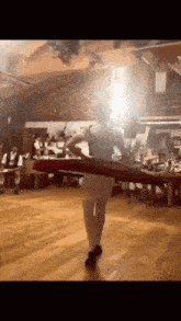 a woman is dancing on a wooden floor in front of a crowd of people