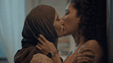 a woman in a hijab kissing another woman