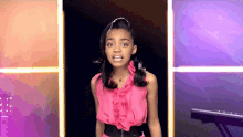 a girl in a pink dress stands in front of a piano