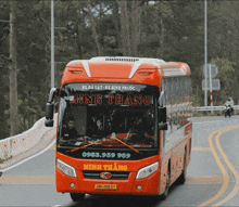 a red minh thang bus is driving down a curvy road