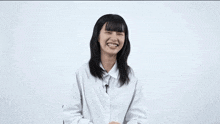 a woman stands in front of a white wall with 555 written in orange letters
