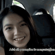 a woman is smiling in a car with a caption that says " aduh nih penampilan itu menguntingkan "