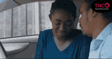 a man and woman in a car with tnc on the bottom