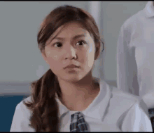 a girl in a school uniform looks at the camera