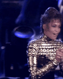 a woman wearing a gold top with diamonds on it