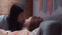a woman kissing another woman on the forehead while laying on a bed