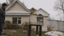 a man standing in front of a house with a table in the foreground