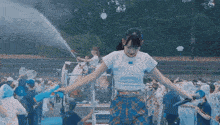a woman holding a water gun in front of a crowd of people