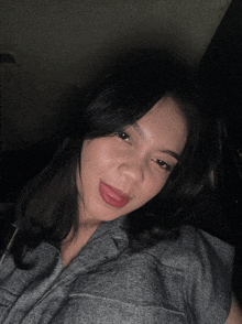 a woman in a gray shirt is sticking her tongue out