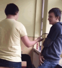 a man in a yellow shirt is talking to another man in a gray shirt