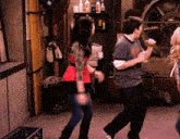 a group of people are dancing in a room in front of a fan