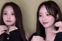 two young women are making a heart shape with their hands .