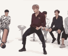 a man in a maroon shirt is dancing in front of a group of people sitting on stools .