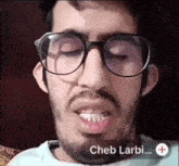 a man with glasses and a beard says cheb larbi on the bottom