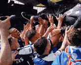 a man is being thrown in the air by a group of people wearing blue jerseys with the number 5 on them