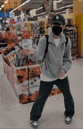 a man wearing a mask and a la hat stands in front of a trick or treat display