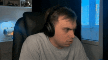 a man wearing headphones is sitting in a chair in front of a window