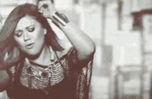 a black and white photo of a woman holding her hair .
