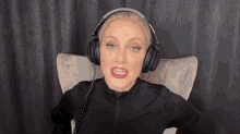 a woman wearing headphones is sitting in a chair with her mouth open