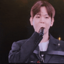 a man in a suit is holding a microphone in front of his face .