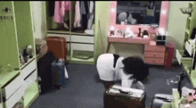 a woman in a white dress is standing in a room with a pink vanity and a mirror .