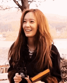 a woman with long red hair is smiling while holding a lighter