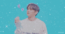 a young man with purple hair is holding a butterfly in his hand