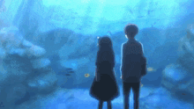 a boy and a girl are standing in front of an aquarium looking at fish