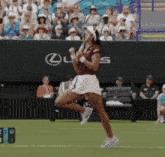 a woman playing tennis in front of a lexus sign