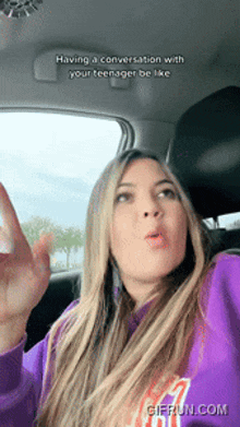 a woman in a purple sweatshirt is in a car