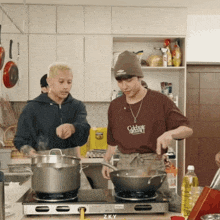 two men are cooking in a kitchen and one of them is wearing a shirt that says cooking