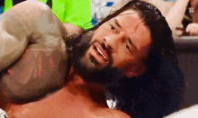 a man with long hair and a beard is laying on the ground with his head on another man 's chest .
