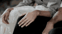 a woman in a white dress is sitting on a man 's lap with her hand on his knee .