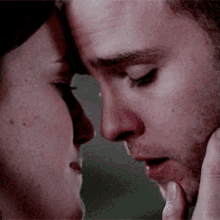 a man and a woman are touching each other 's faces .
