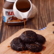 a bottle of nutella sits on a wooden table next to some cookies
