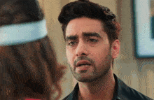 a man with a beard is looking at a woman with a headband on her head .