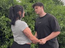 a man and a woman are holding hands and the man is wearing a t-shirt that says " fuck society "