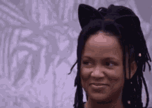 a woman with dreadlocks is wearing a cat ear headband .
