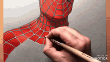 a person is drawing a spider man on a piece of paper with a brush