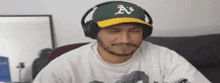 a man wearing headphones and a hat with the letter a on it is smiling .