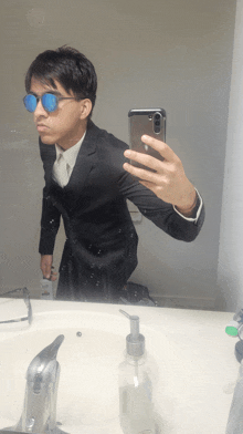 a man in a suit takes a selfie in front of a mirror