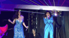 a woman in a blue dress sings into a microphone