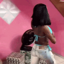 a woman is standing in front of a fan in a pink room