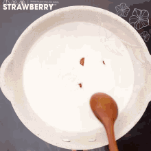a pot of strawberry flavored liquid with a wooden spoon